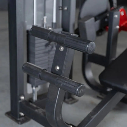 Close-up of black cylindrical handles on a selectorized abdominal crunch machine with metal frame and adjustment mechanisms visible in a gym setting.