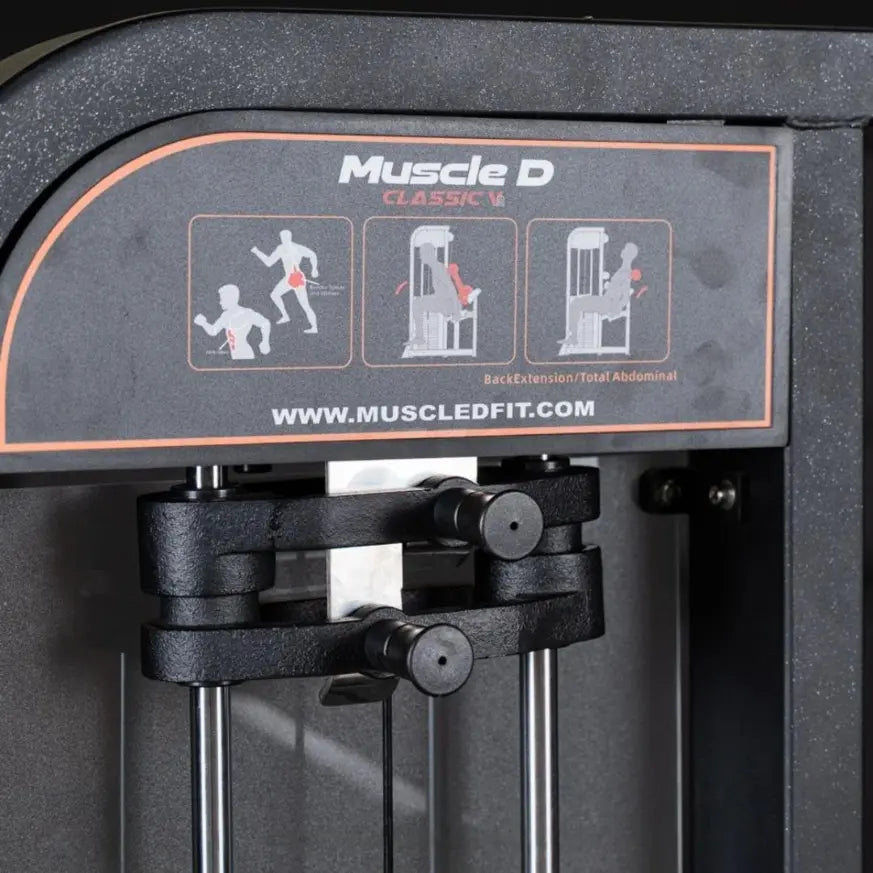Muscle D Classic V2 selectorized back and abdominal combination machine with black frame, orange accent trim, and instruction placards showing three exercise positions on the top panel.