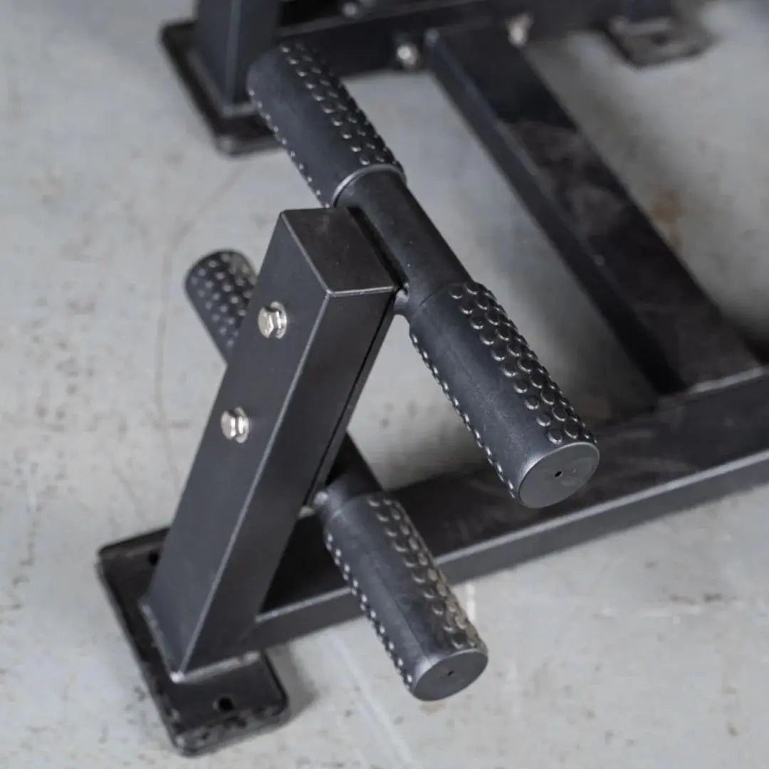Close-up of textured black handles with white stitching on a selectorized back and ab combo machine, showing the metal frame and adjustment mechanisms.