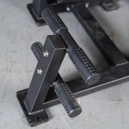 Close-up of textured black handles with white stitching on a selectorized back and ab combo machine, showing the metal frame and adjustment mechanisms.