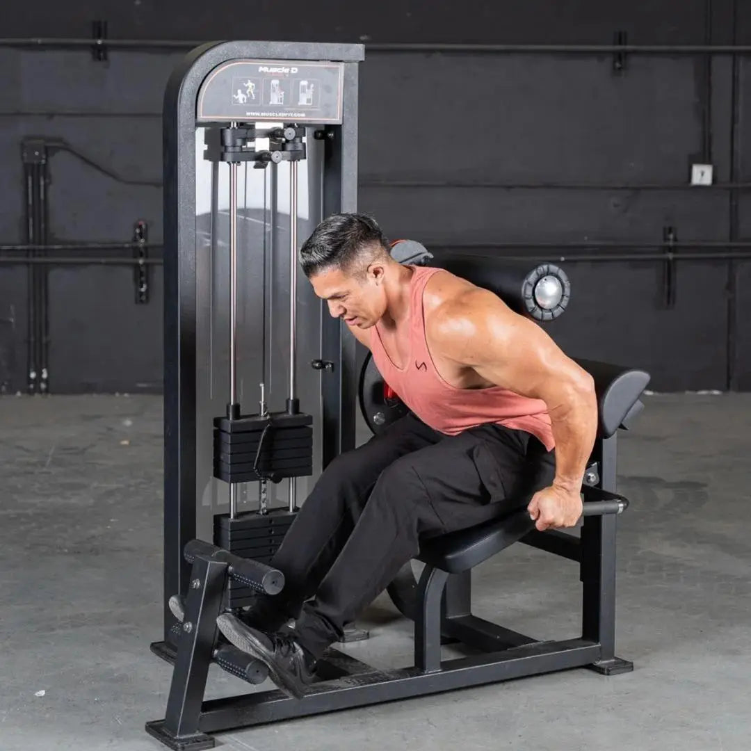 Man performing back and ab exercise on a Muscle D selectorized machine with black frame and gray accents in a gym setting.