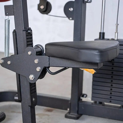 Close-up of a biceps and triceps combo machine showing the black padded arm rest, adjustment bracket with metal bolts, and selectorized weight plate stack in the background.