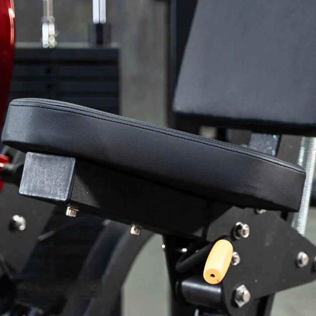 Black padded seat pad with stitched seams on a selectorized chest press machine, showing the adjustment mechanism and yellow selector pin below.