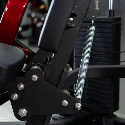 Close-up of selectorized chest press machine mechanics showing chrome spring adjustment rod, black metal frame with bolts, and weight stack on dark background.
