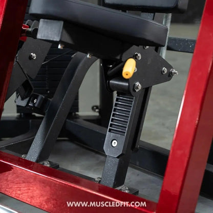 Close-up of selectorized chest press machine mechanics showing yellow weight pin, black metal frame, and adjustment lever on red equipment frame.