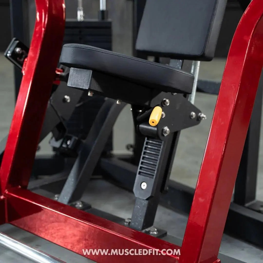 Red and black selectorized chest press machine with padded seat and backrest, yellow weight selector pin, and metal frame in a gym setting.