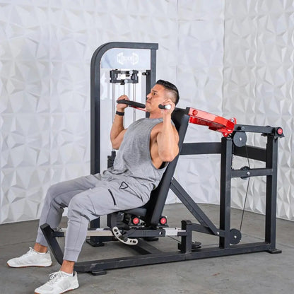 Man performing a chest and shoulder exercise on a black selectorized machine with red accents and cable-driven arms in a studio setting.