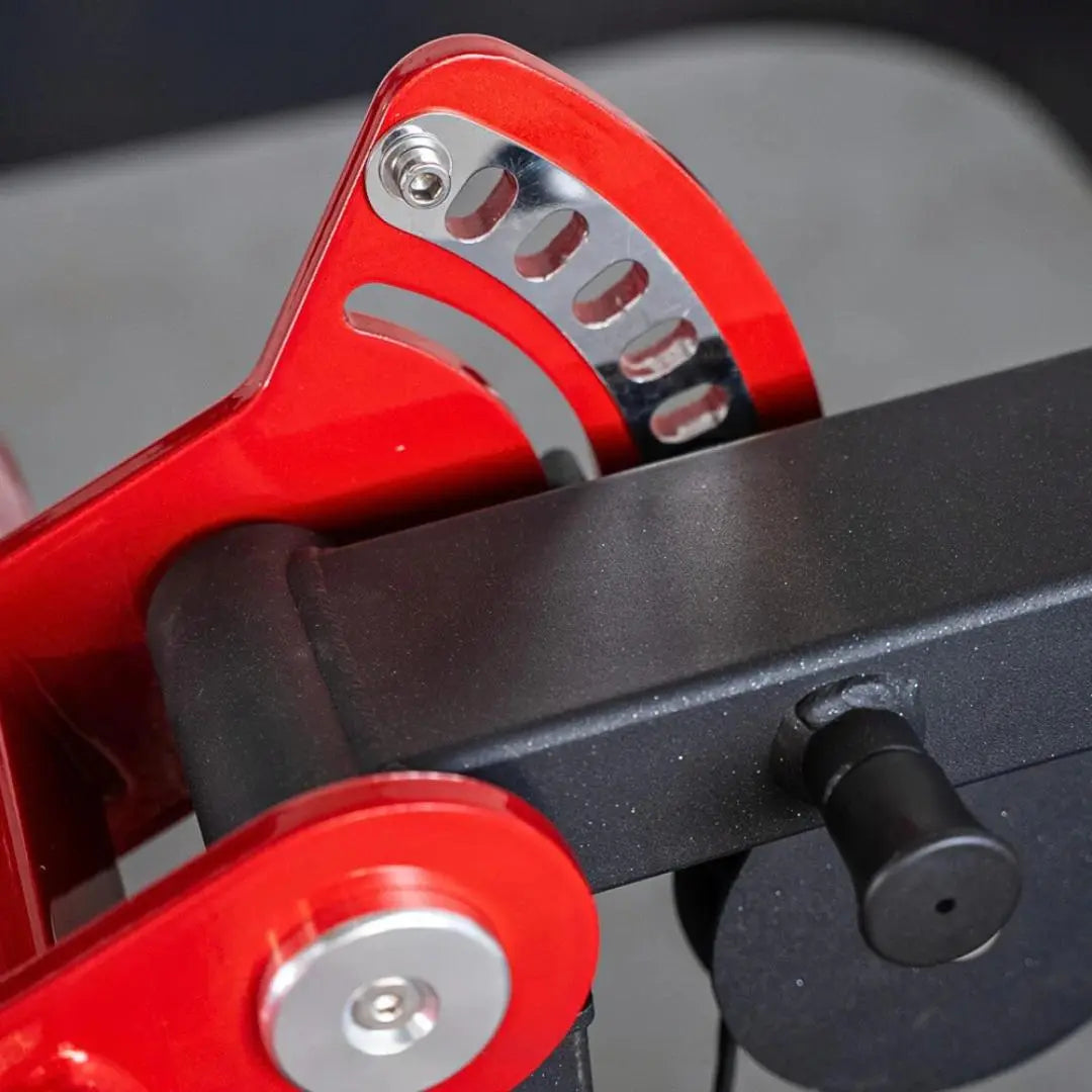 Close-up of red weight stack selector pin and red arm lever on a black selectorized chest and shoulder machine with metal adjustment knobs.
