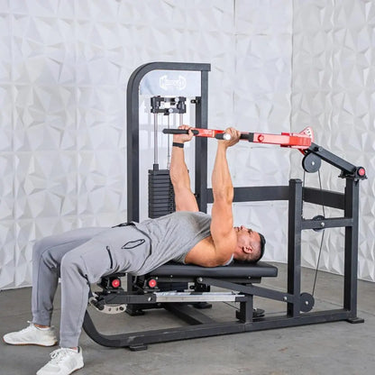 Man performing a chest press exercise on a black and red selectorized machine with weight stack and adjustable arm lever against a white textured wall.