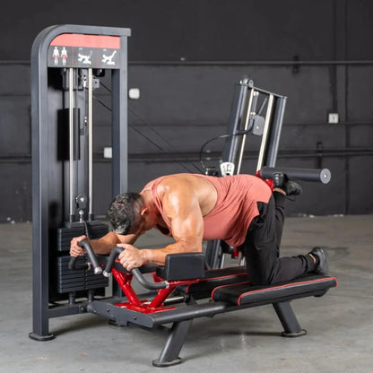 Man performing a glute kick exercise on a red and black selectorized machine with gray frame and overhead weight stack in a gym setting.