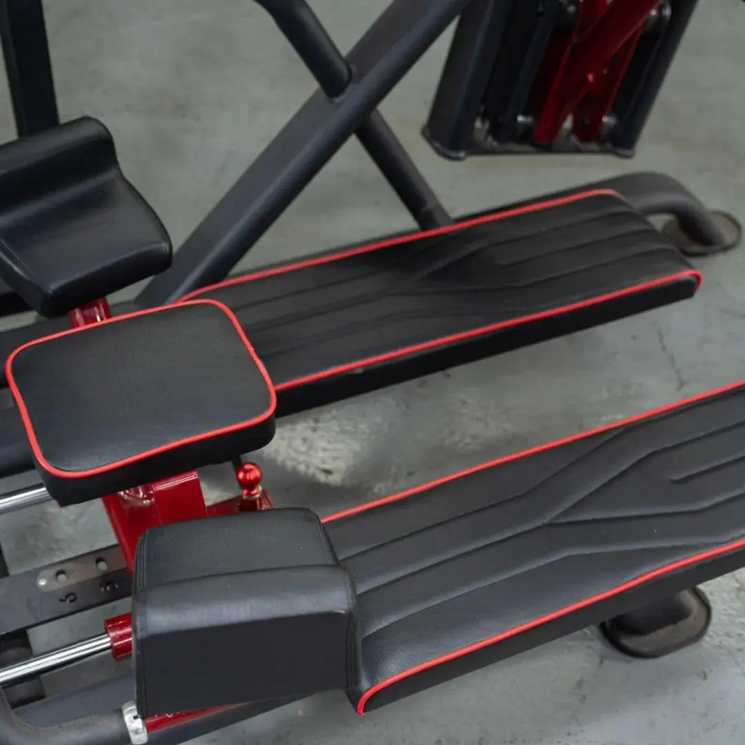 Black and red glute kick machine with padded foot platform, leg rest, and red metal frame accents on a concrete gym floor.