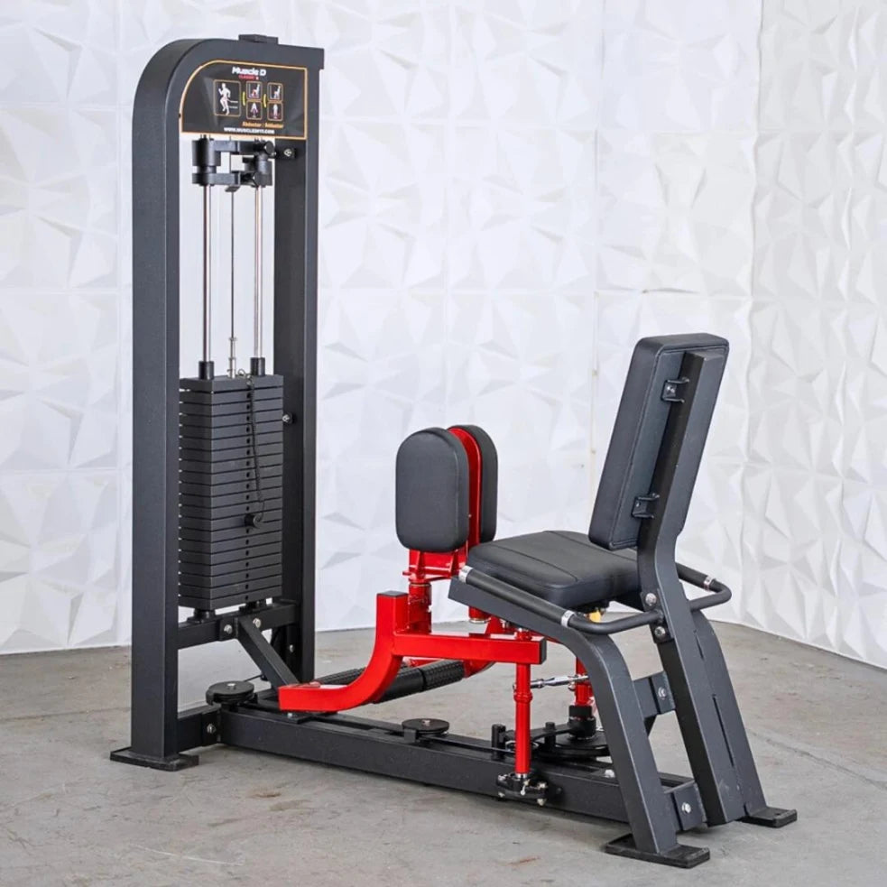 Black and red selectorized inner and outer thigh combo machine with stacked weight plates on the left tower, padded seat in the center, and footrest platform, set against a white textured backdrop.