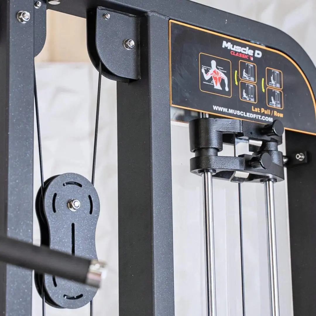 Close-up of a Muscle D Classics selectorized lat pulldown and low row combo machine showing the weight pin selector on the left side and instruction decal with exercise diagrams on the dark frame.