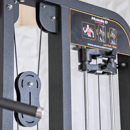 Close-up of a Muscle D Classics selectorized lat pulldown and low row combo machine showing the weight pin selector on the left side and instruction decal with exercise diagrams on the dark frame.