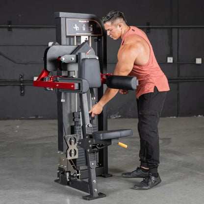 Man performing a lateral raise on a black and red selectorized machine with digital display in a gym setting.