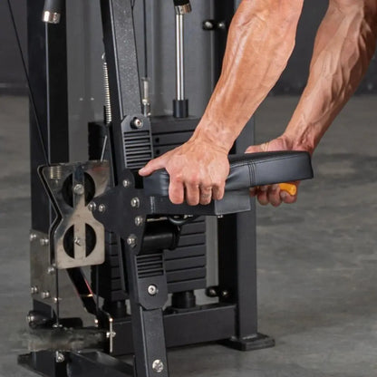 Man's hand gripping the padded handle of a black selectorized lateral raise machine during exercise, showing the machine's mechanical arm and weight stack in a gym setting.