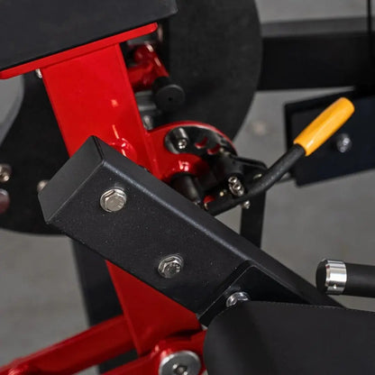 Close-up of red and black leg extension machine showing black foot pad with chrome bolts, red frame, and yellow handle grip.