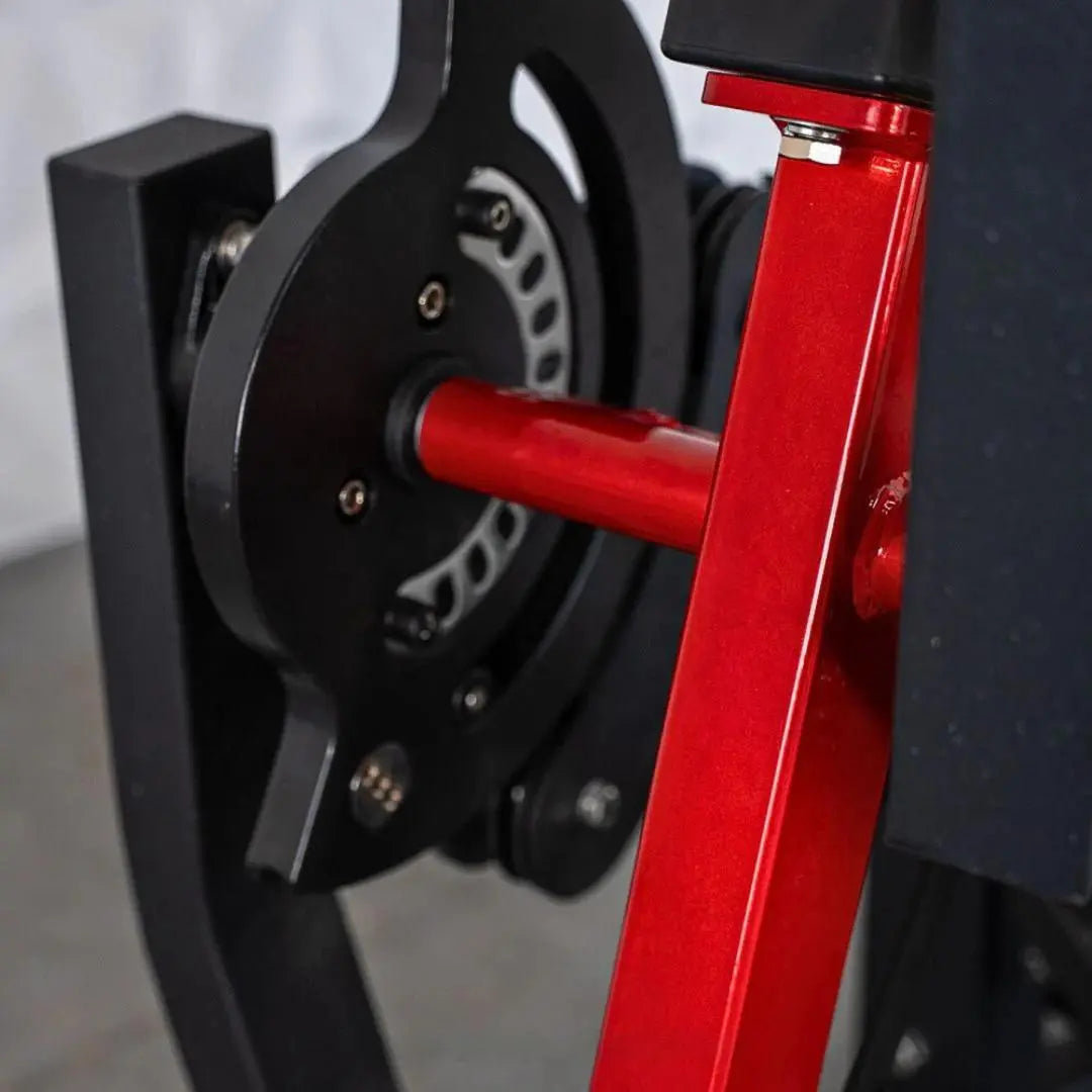 Close-up of a selectorized leg extension and leg curl machine with a black weight stack, red frame, and adjustment handle.