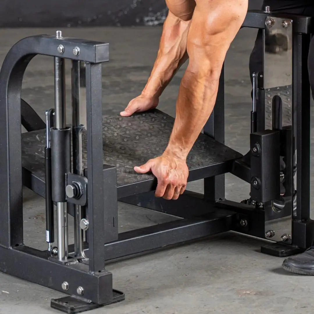 Man performing a glute exercise on a black commercial multi-hip machine with dual platforms and adjustment handles in a gym setting.