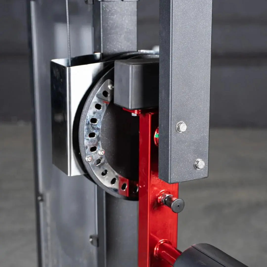 Close-up of the hip machine's weight stack mechanism, showing a selectorized pin selector with multiple holes on a black and red frame mounted to gray steel uprights.