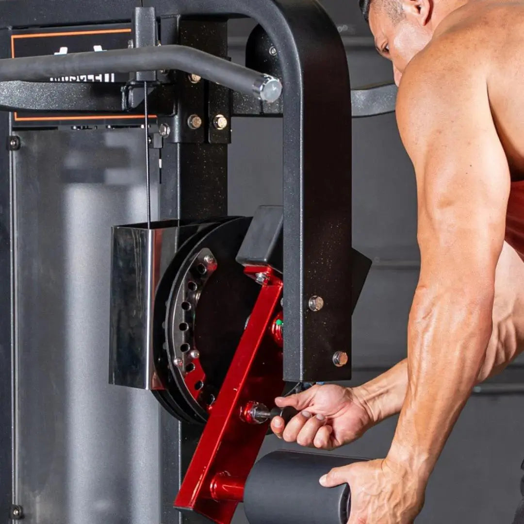 Man using a multi-hip machine with black frame, red lever, and weight stack, performing a hip exercise in a gym setting.