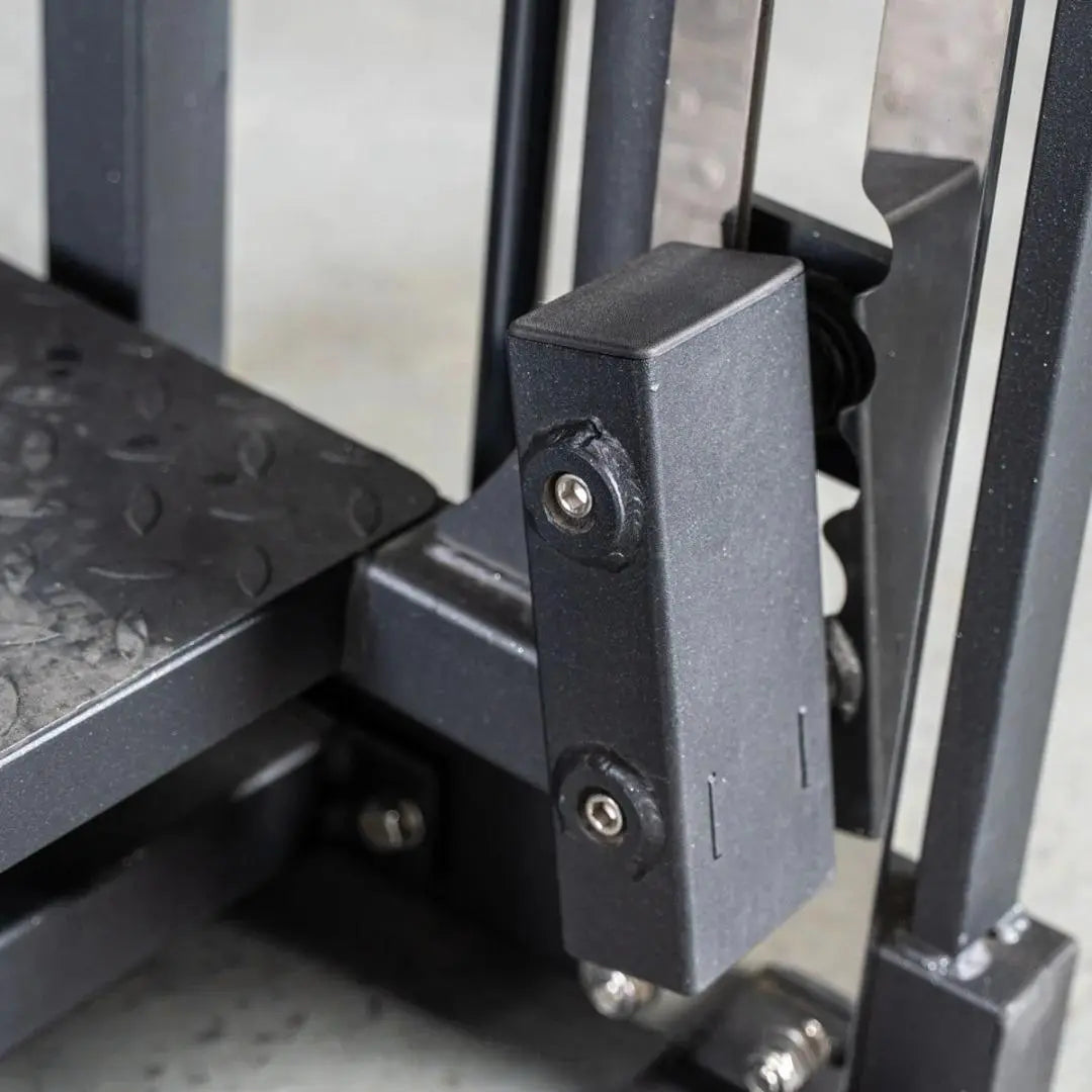 Close-up of the adjustment mechanism on a multi-hip machine, showing a black selector pin with metal fasteners and textured grip surfaces on the frame.