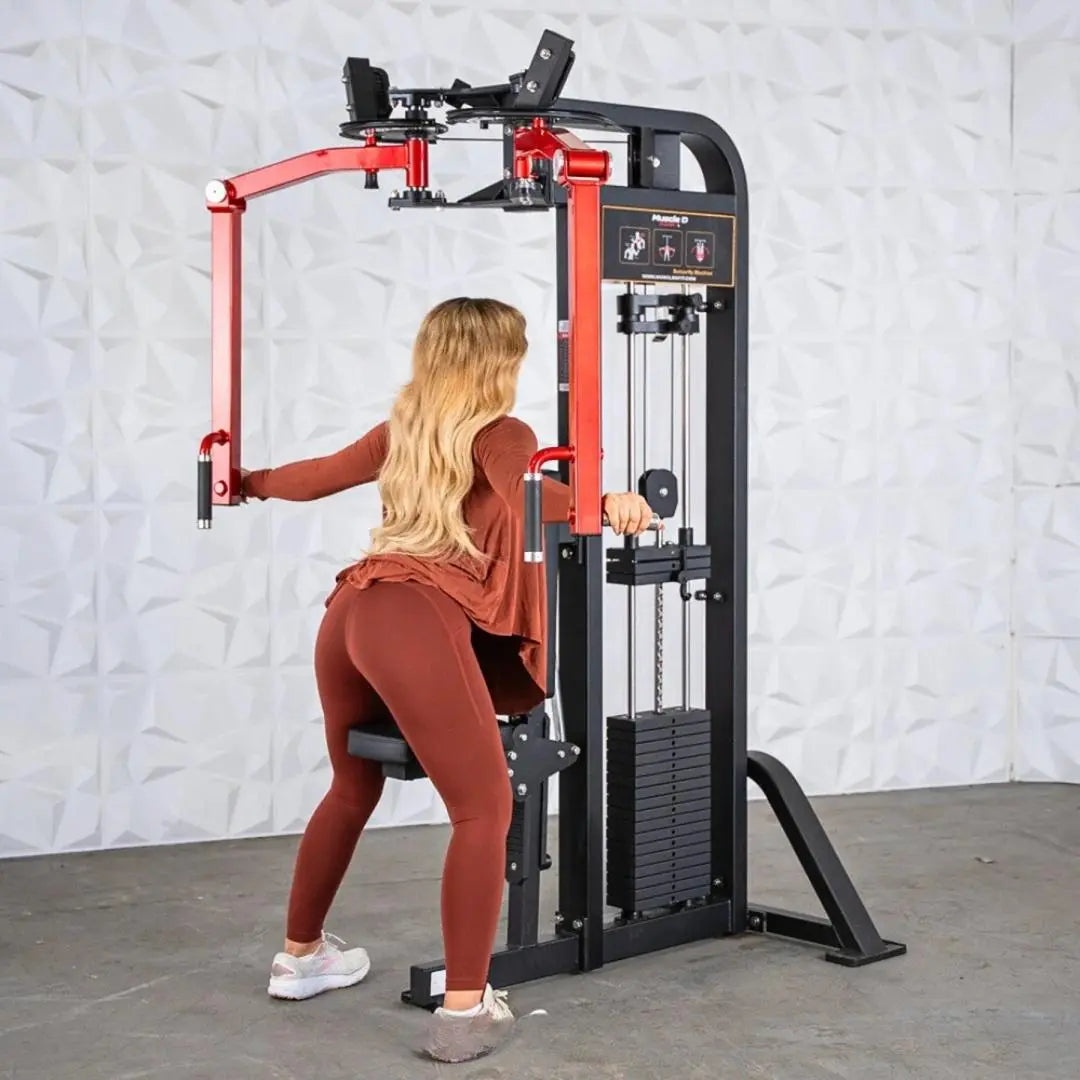 Woman performing a chest fly exercise on a red and black selectorized pec and rear delt combo machine with weight stack and control panel.