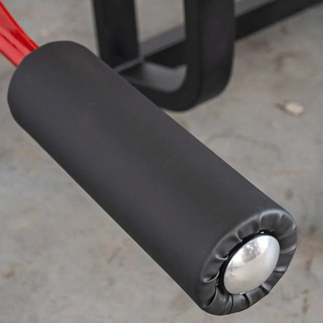 Close-up of the padded leg curl attachment on a selectorized leg curl machine, showing the black foam pad and white circular pivot point.