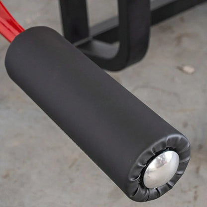 Close-up of the padded leg curl attachment on a selectorized leg curl machine, showing the black foam pad and white circular pivot point.