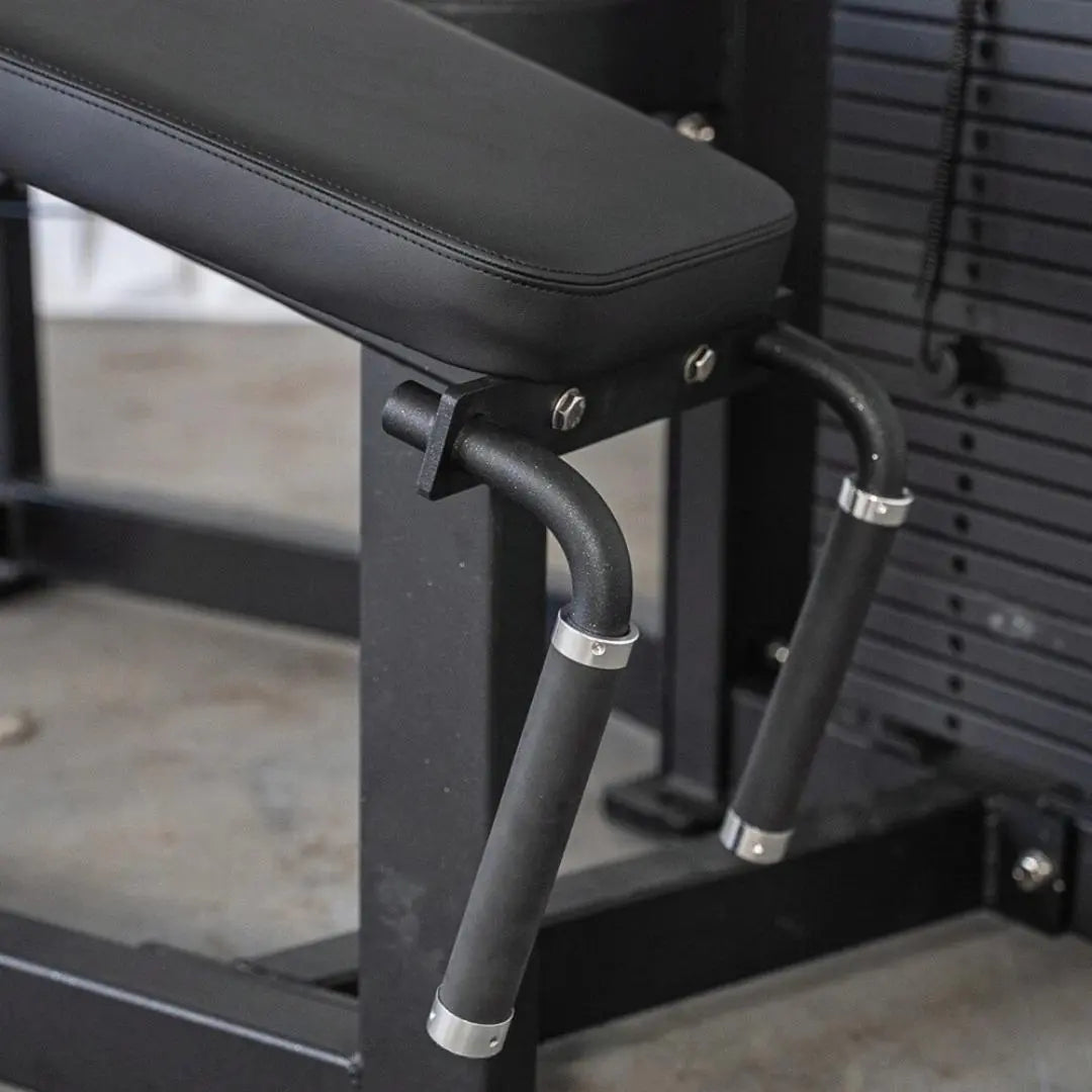 Black selectorized prone leg curl machine with padded lever arm and cushioned seat in a gym setting.