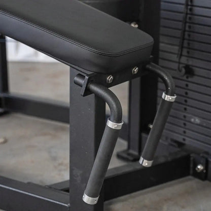 Black selectorized prone leg curl machine with padded lever arm and cushioned seat in a gym setting.