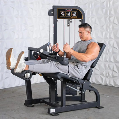 Man performing seated leg curl on a black Muscle D Fitness selectorized machine with weight stack and instruction graphics on the upper panel.