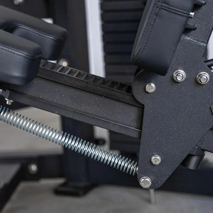 Close-up of seated leg curl machine components showing black padded leg attachment with metal adjustment bolts, chrome hardware, and threaded rod mechanism.
