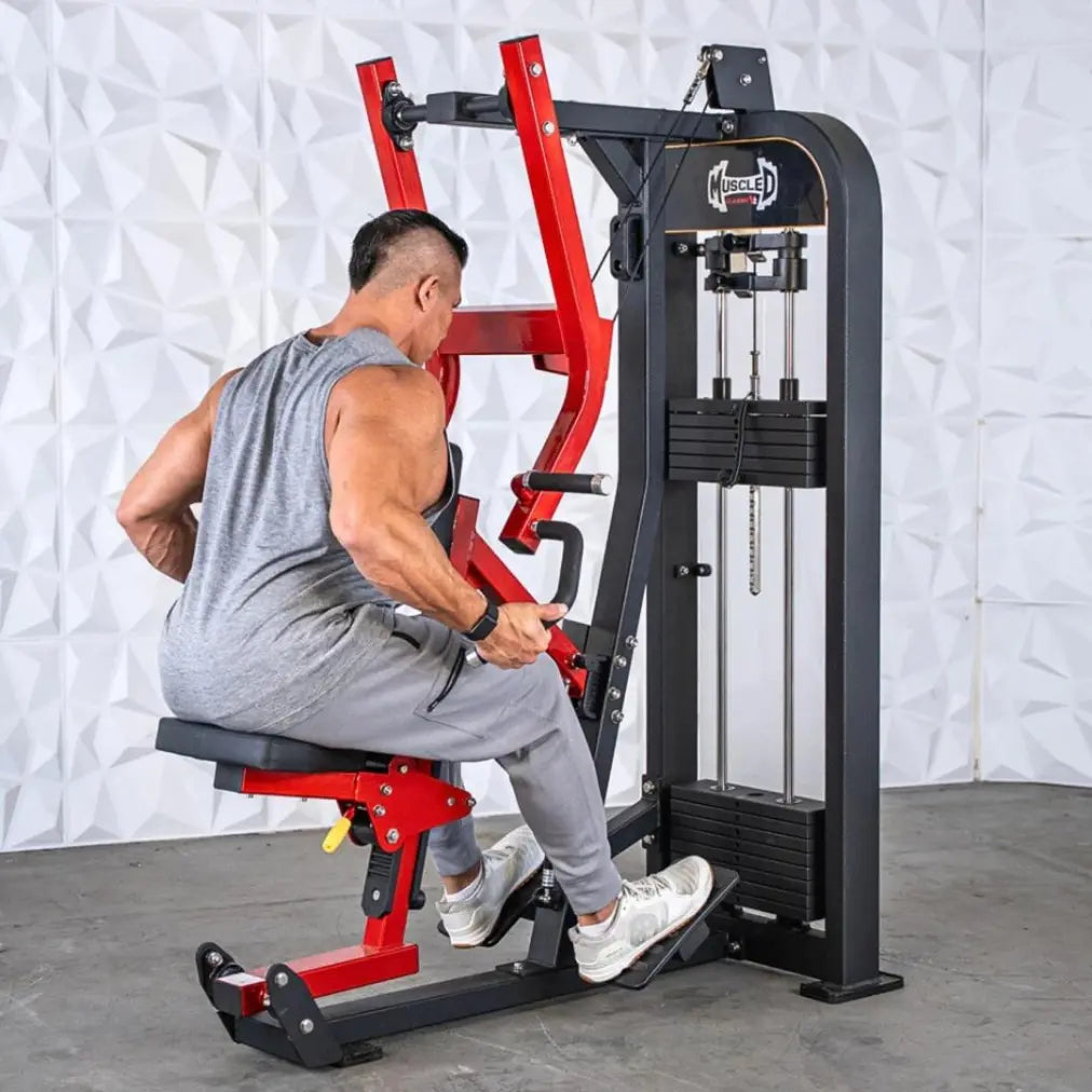 Man performing seated row on a commercial machine with red frame, black padded seat, and dual cable columns against a white textured wall.