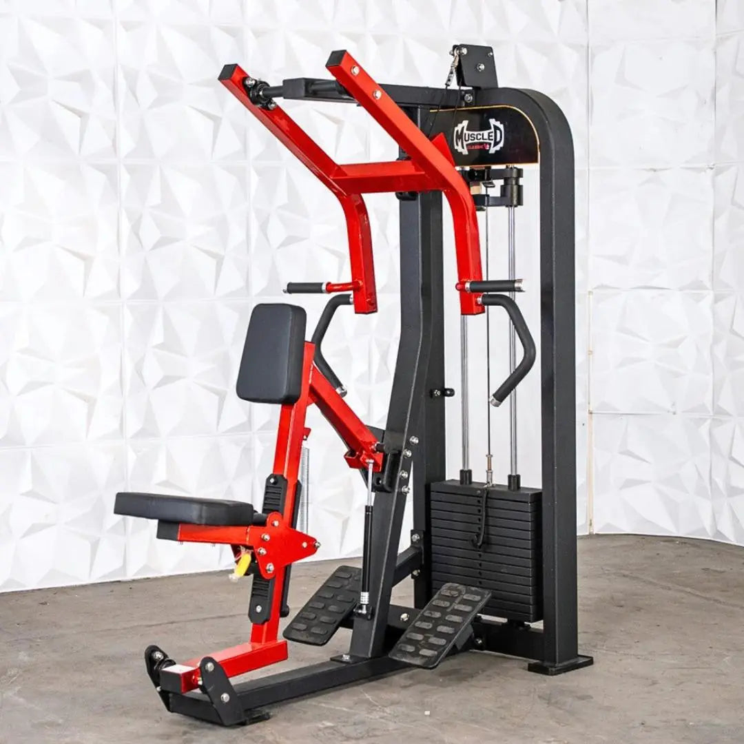 Red and black selectorized seated row machine with padded backrest, foot platform, and cable-driven resistance system on concrete floor against white textured backdrop.