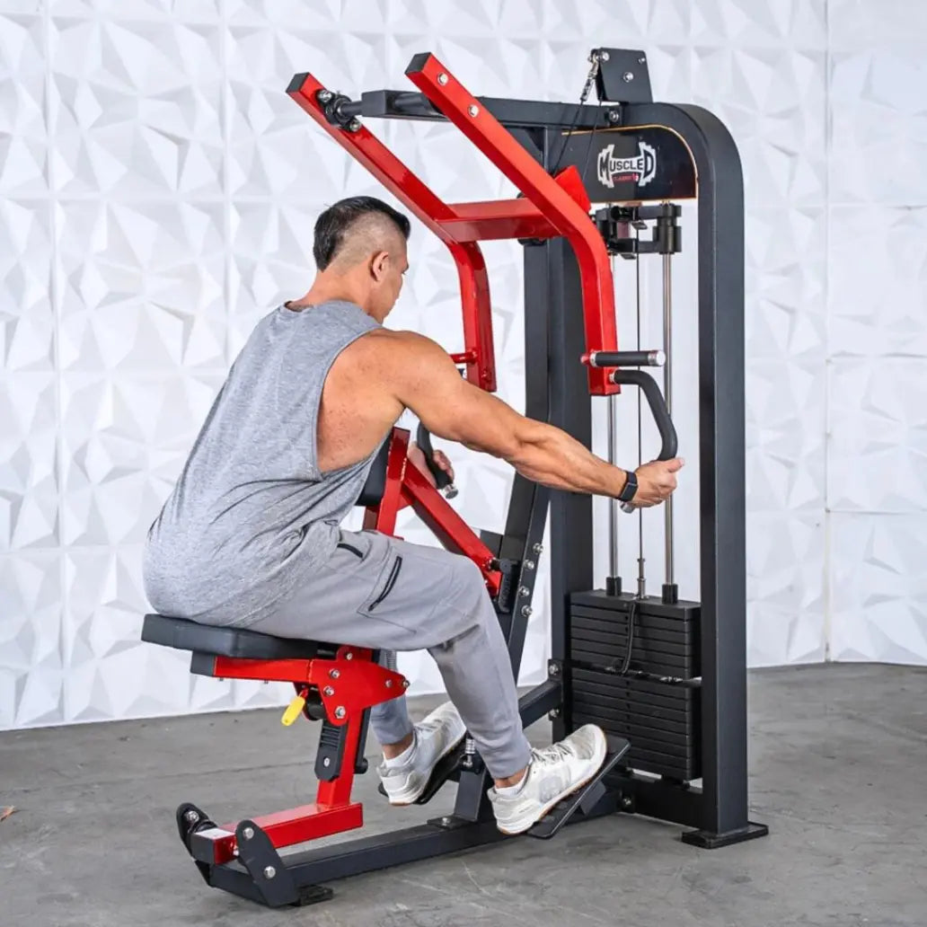 Man performing seated row on a commercial selectorized machine with red and black frame and weight stack on white textured wall background.
