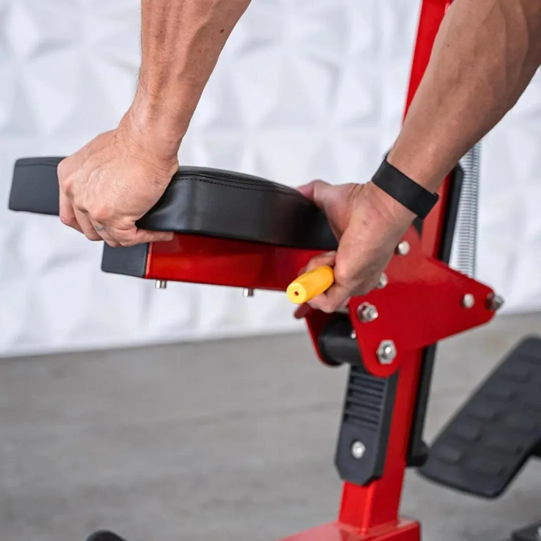 Man gripping the black padded handle of a red seated row machine with metal hardware and yellow adjustment pin visible.