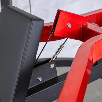 Close-up of a red and black selectorized shoulder press machine showing the padded seat back, metal frame, cable attachment, and adjustment bolts.