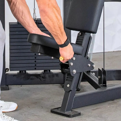 Man performing shoulder press on a black selectorized shoulder press machine with padded seat and foot platform in a gym setting.