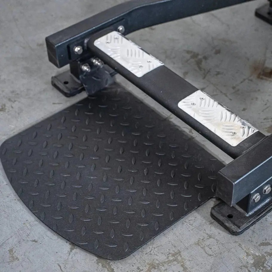 Black selectorized standing calf raise machine with textured diamond-plate footplate and dual white weight selector pins mounted on the frame.