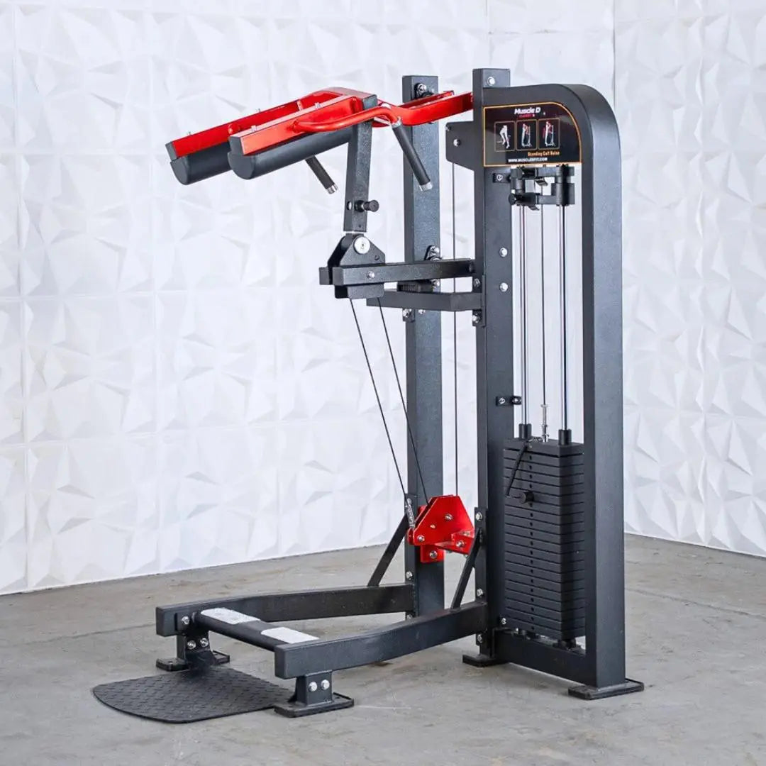 Commercial standing calf raise machine with gray steel frame, red padded shoulder harness, cable-driven resistance system, and instructional diagrams on the control panel.