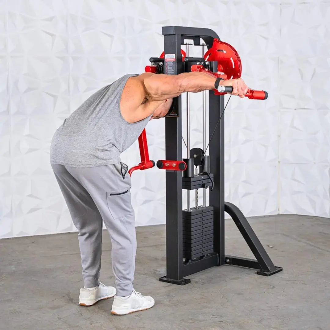 Man performing standing lateral raise on a selectorized machine with red handles, black frame, and weight stack visible on the side.