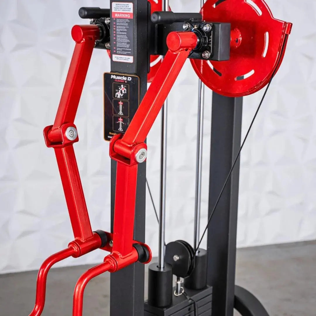 Red and black selectorized standing lateral raise machine with dual articulating arms, weight plate storage on right side, and instruction placard on central column.