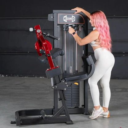 Woman performing triceps extension on a black and red selectorized machine in a gym setting. The machine features a red lever arm and weight stack storage on the black frame.