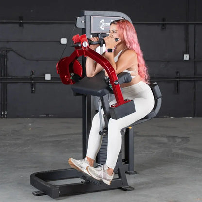 Woman performing triceps extension on a red and black commercial selectorized machine with digital display in a gym setting.
