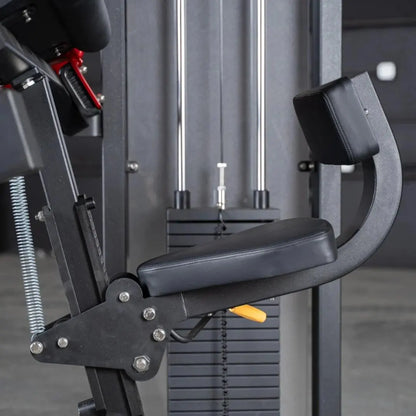 Commercial triceps extension machine with black padded arm rest and seat, chrome vertical guide rods, and weight stack visible in background.