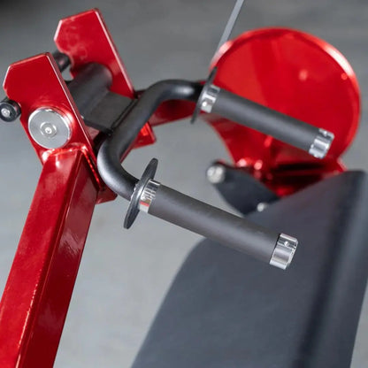 Close-up of red selectorized triceps extension machine with black curved handle bar, red flywheel, and adjustment mechanisms against gray background.
