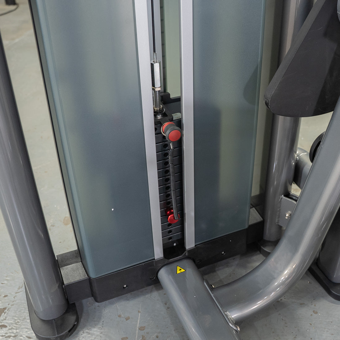 Gym machine weight stack with red selector pin.