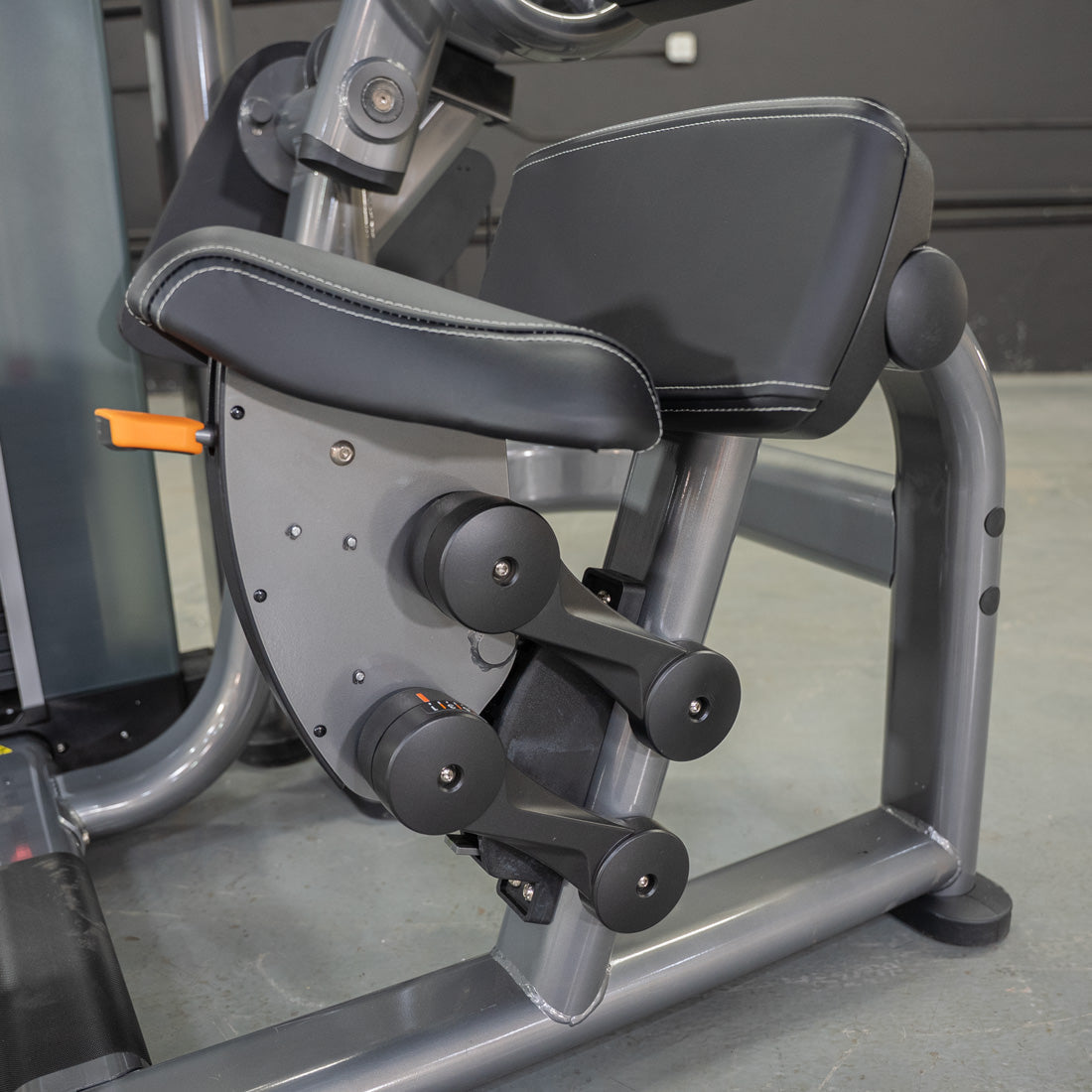 Seated leg curl machine with adjustable pads and sleek grey finish.
