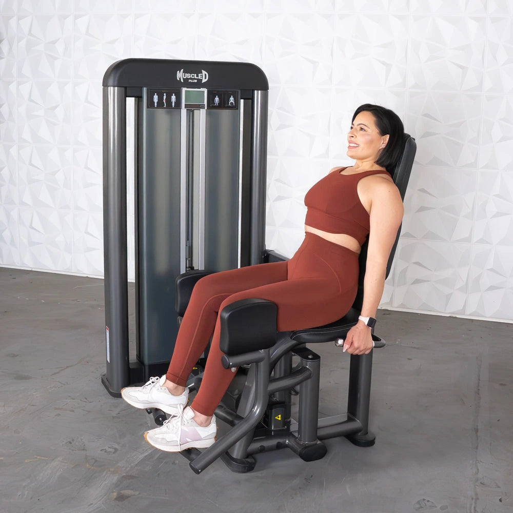 Woman seated on Muscle D Elite Plus Outer Thigh Machine performing a leg exercise.